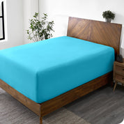 A diagonal view of a bed with just a fitted sheet on it