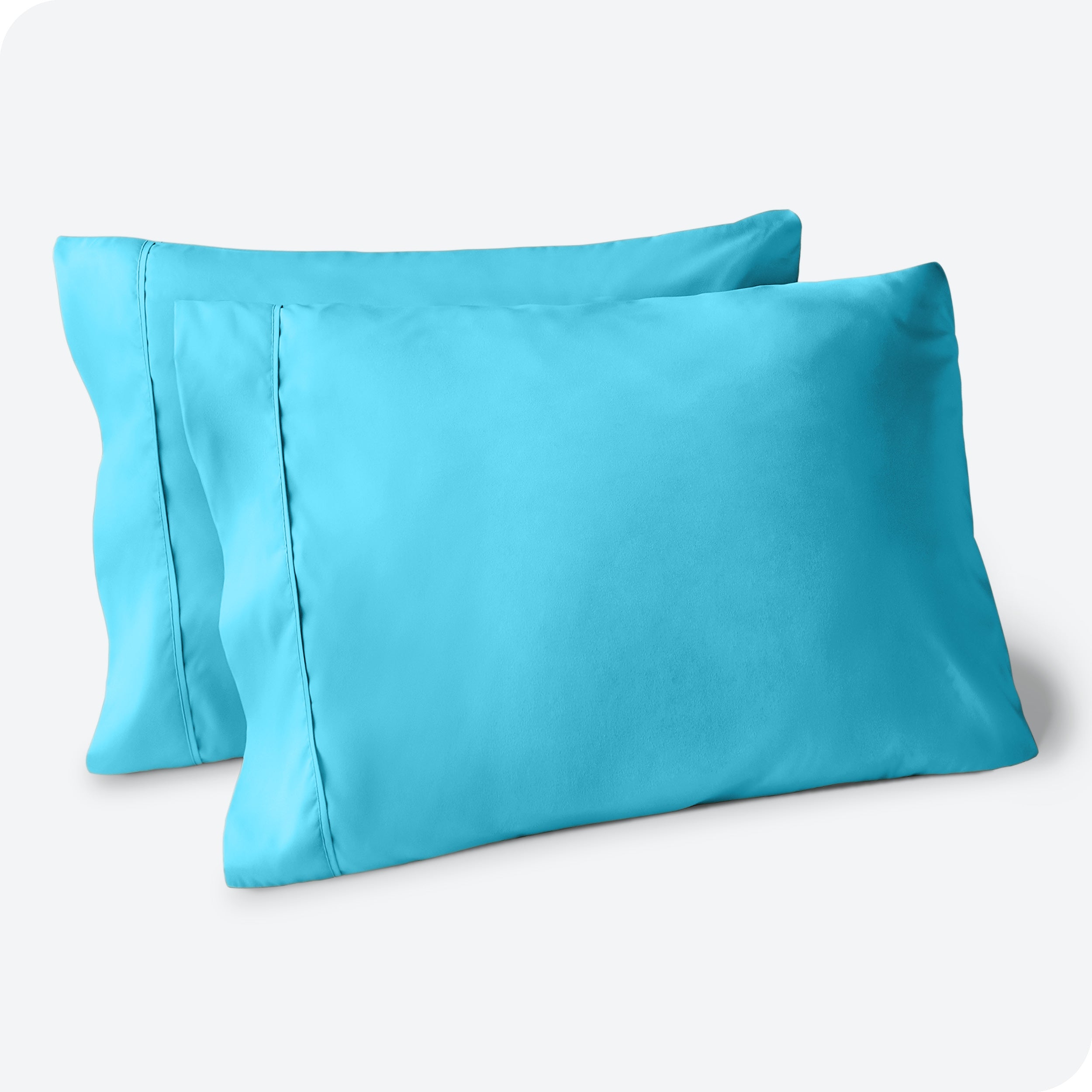 Two pillows on a white background with aqua pillowcases on them