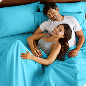 A couple is relaxing in bed with pillows behind them