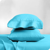 Two pillowcases on pillows stacked on a bed with matching sheets