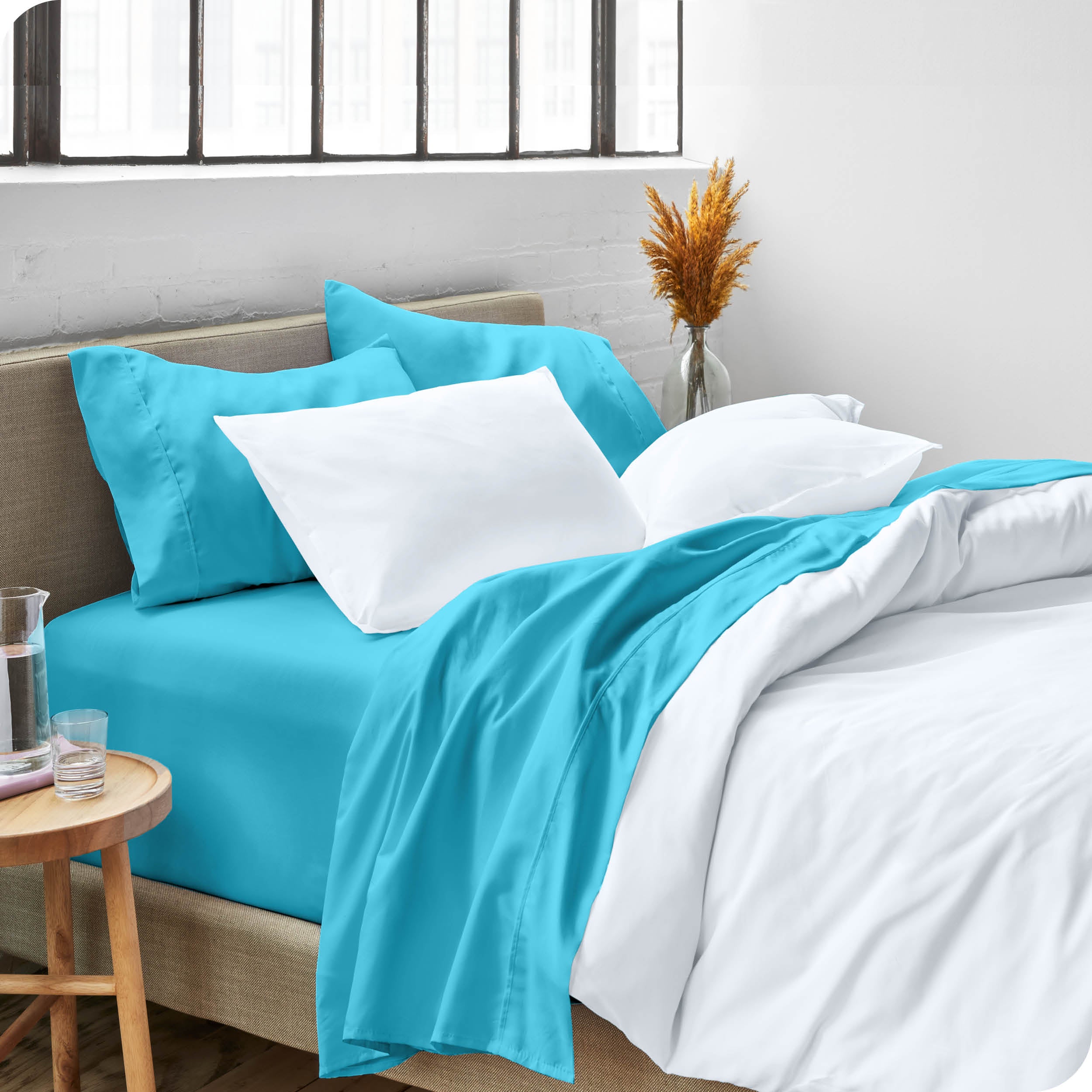 A modern bed made with a microfiber sheet set and duvet set. The duvet set and sheet set are folded over part way down the bed.