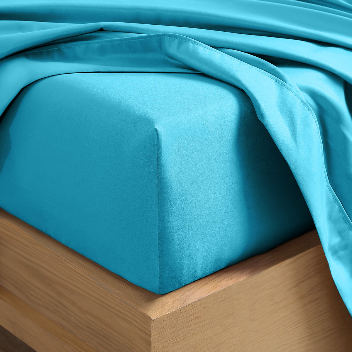 Close up of the corner of a mattress with a fitted sheet and flat sheet on it
