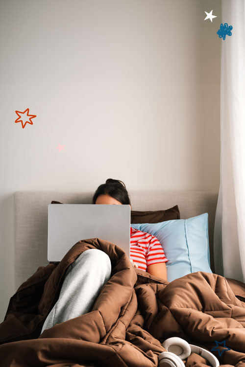 College Student in Dorm IN Bed on computer