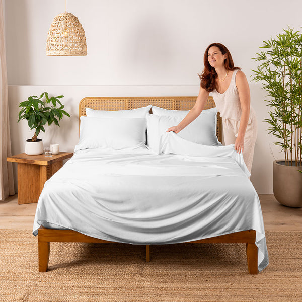 Woman making a bed with cooling white  bamboo sheets