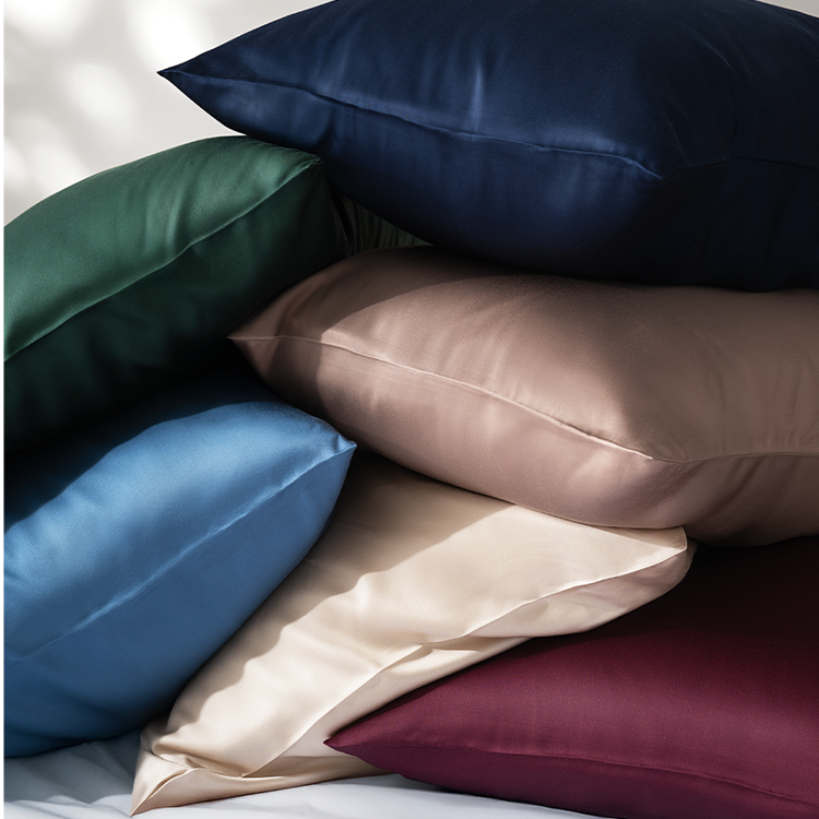 Stack of multicolored satin pillows on a neutral background