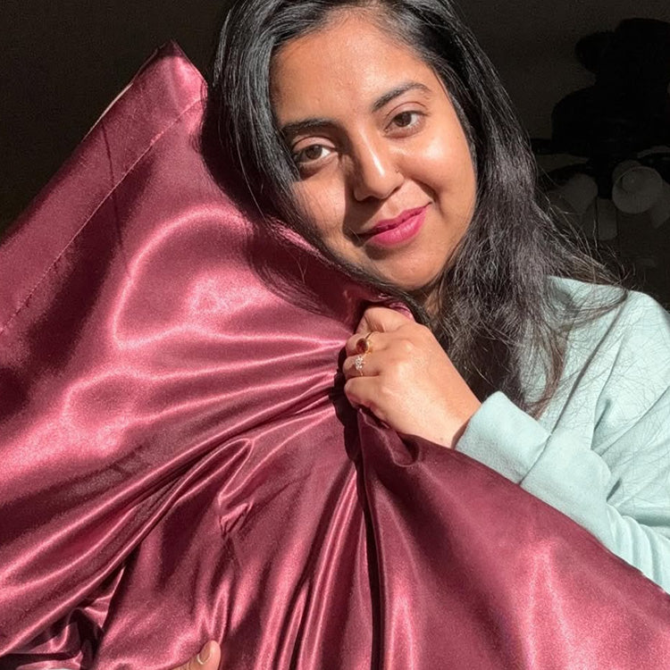 Woman holding a pink satin fabric against a dark background