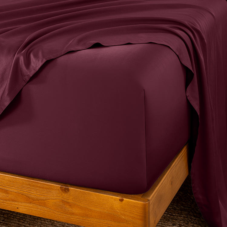 Maroon bed sheets on a wooden bed frame