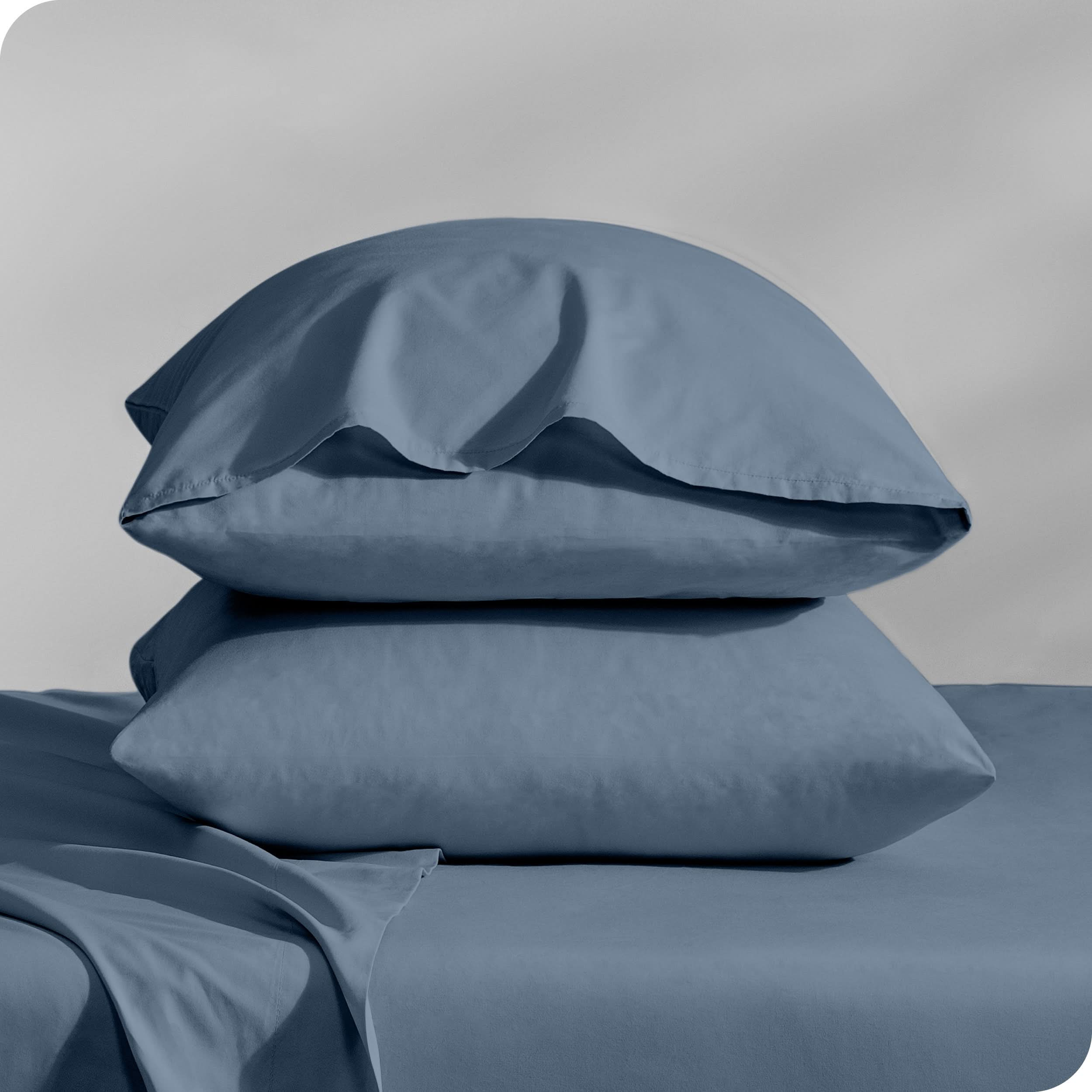 Pillows inside percale pillowcases stacked on a bed
