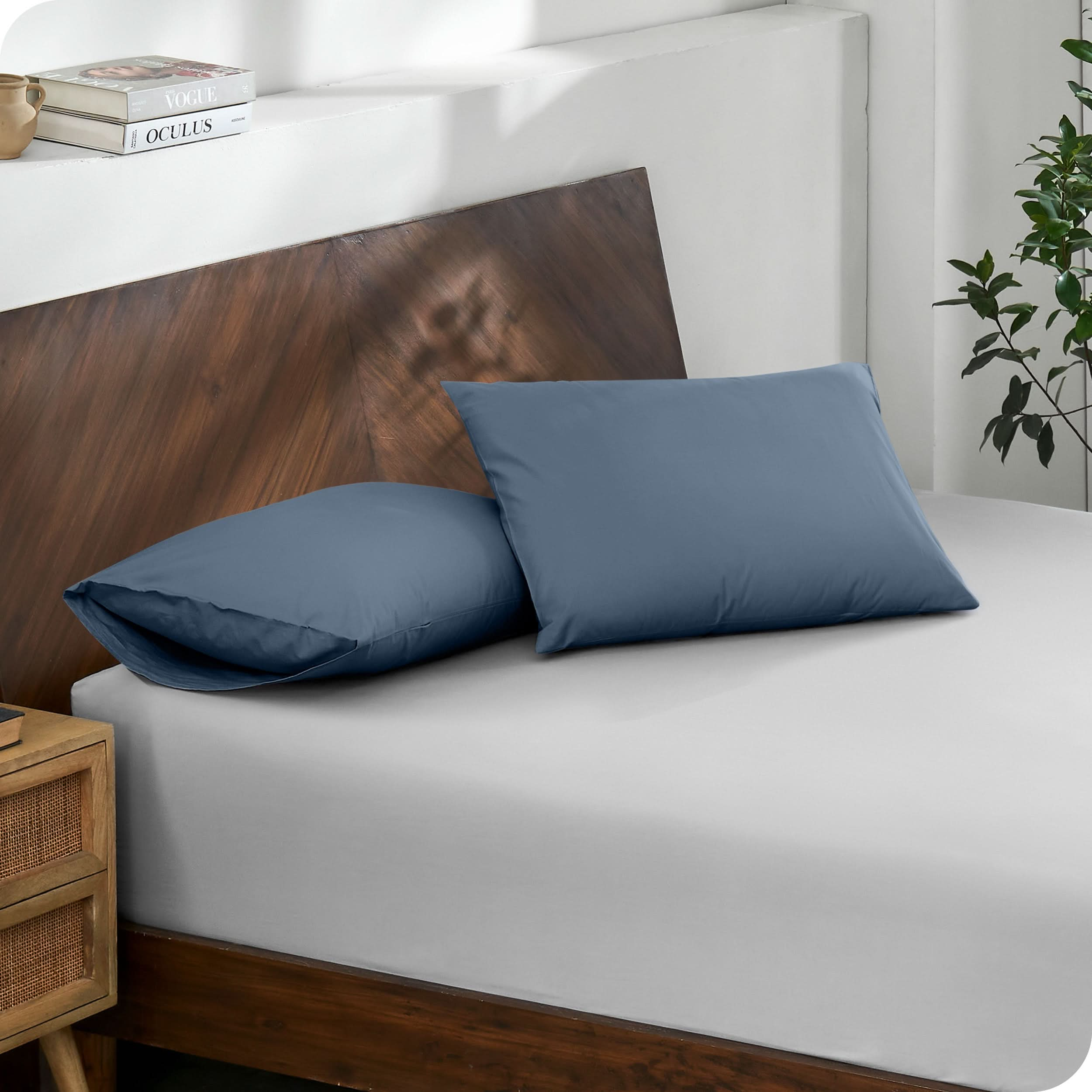 Diagonal view of modern wood bed with a fitted sheet and pillowcases
