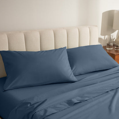 Percale bed sheets and pillowcases on a neatly made bed with a beige headboard.