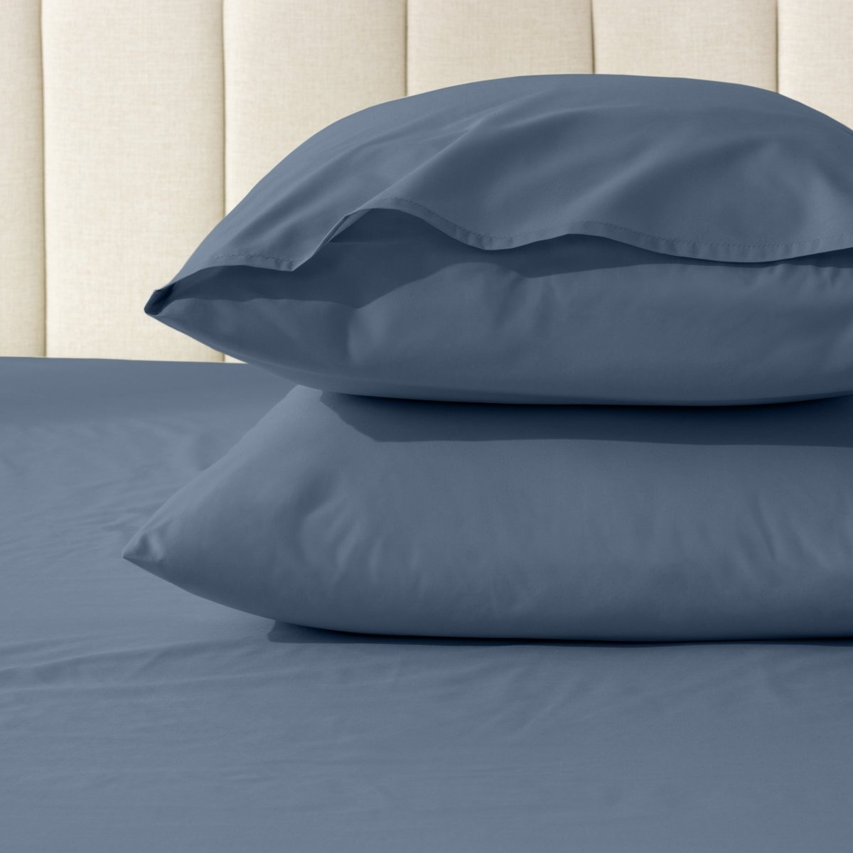 Two pillows stacked on a bed with percale pillowcases on them