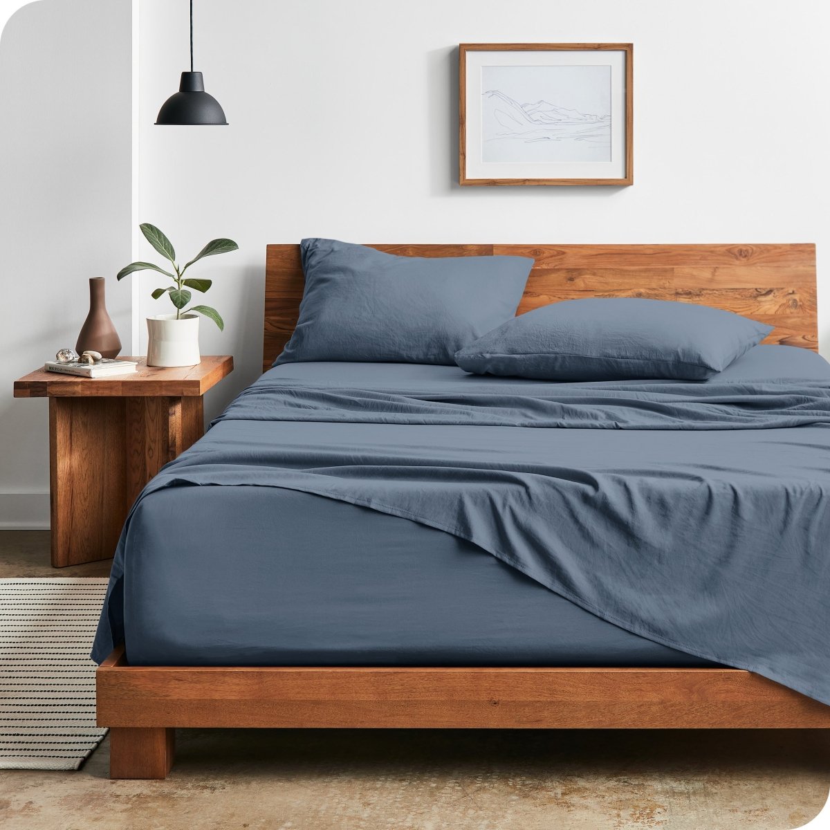 Modern bedroom with washed sheets draped over the end and the side of the bed