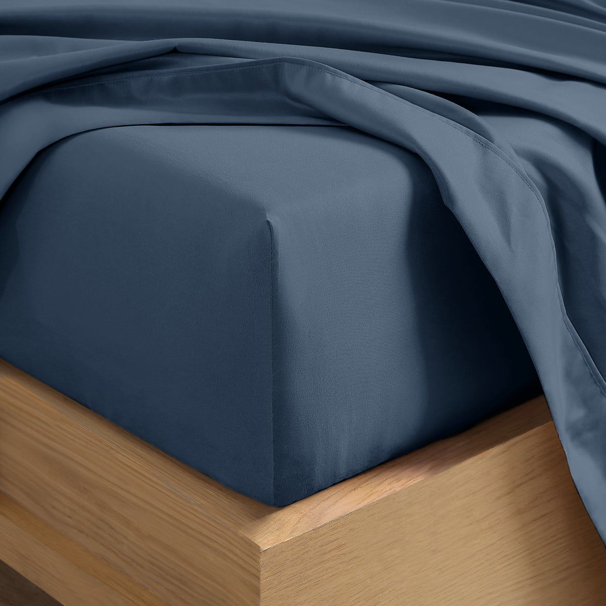 Close up of the corner of a mattress with a fitted sheet and flat sheet on it