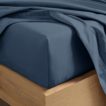 Close up of the corner of a mattress with a fitted sheet and flat sheet on it