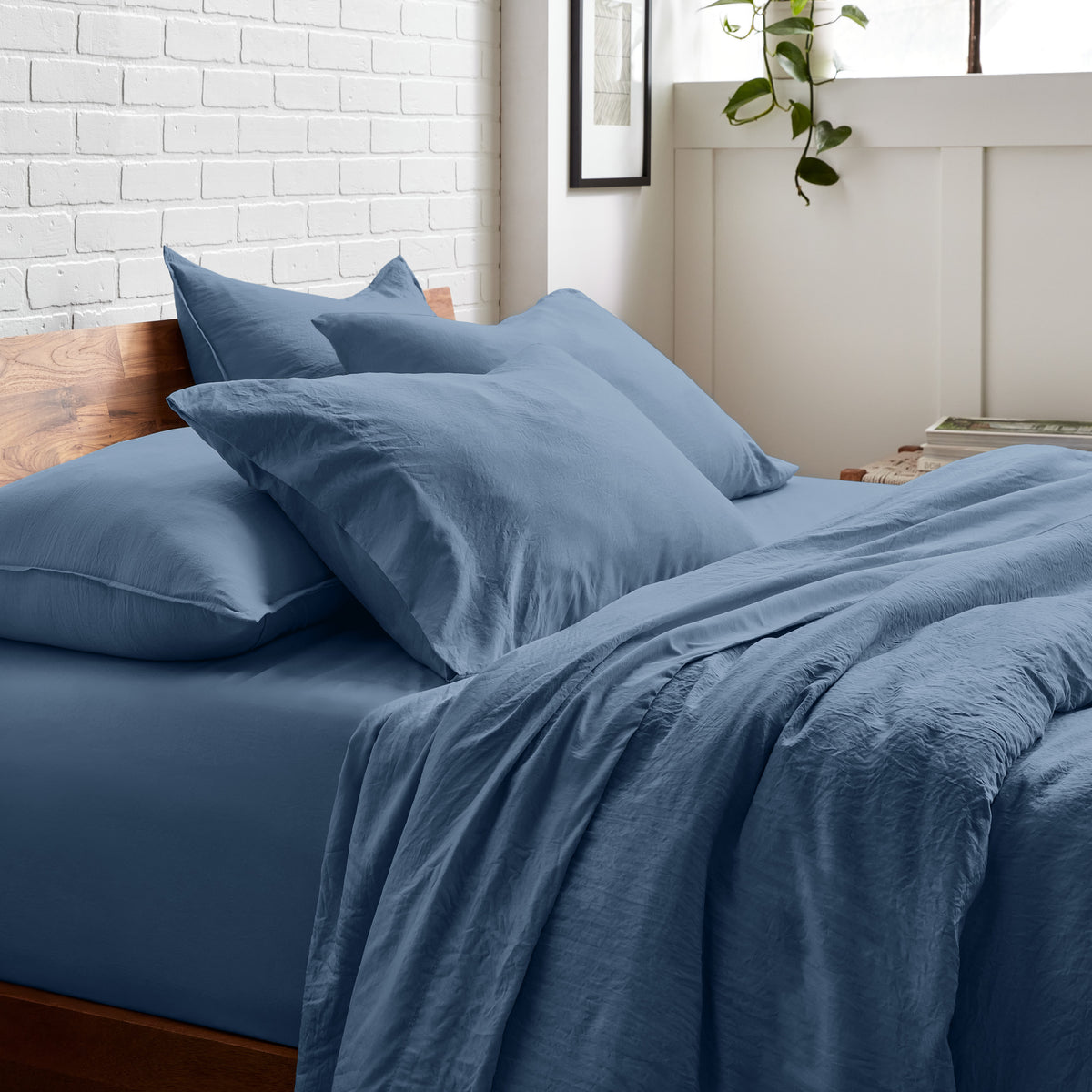 Bedding set on a bed with a white brick wall and window in the background