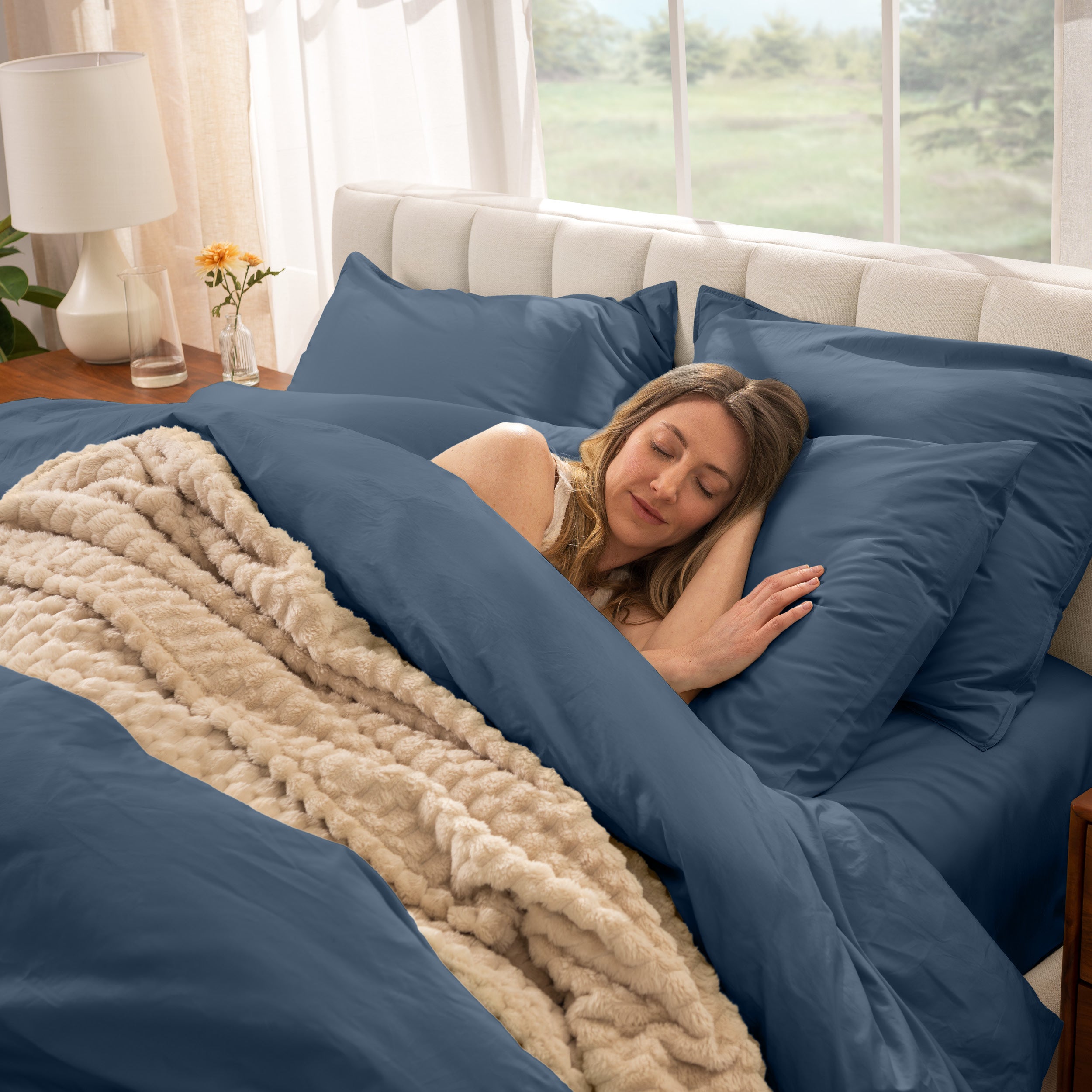 Woman sleeping in a bed with percale bedding and beige blanket