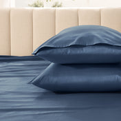 Two pillows stacked on a bed with a beige headboard.