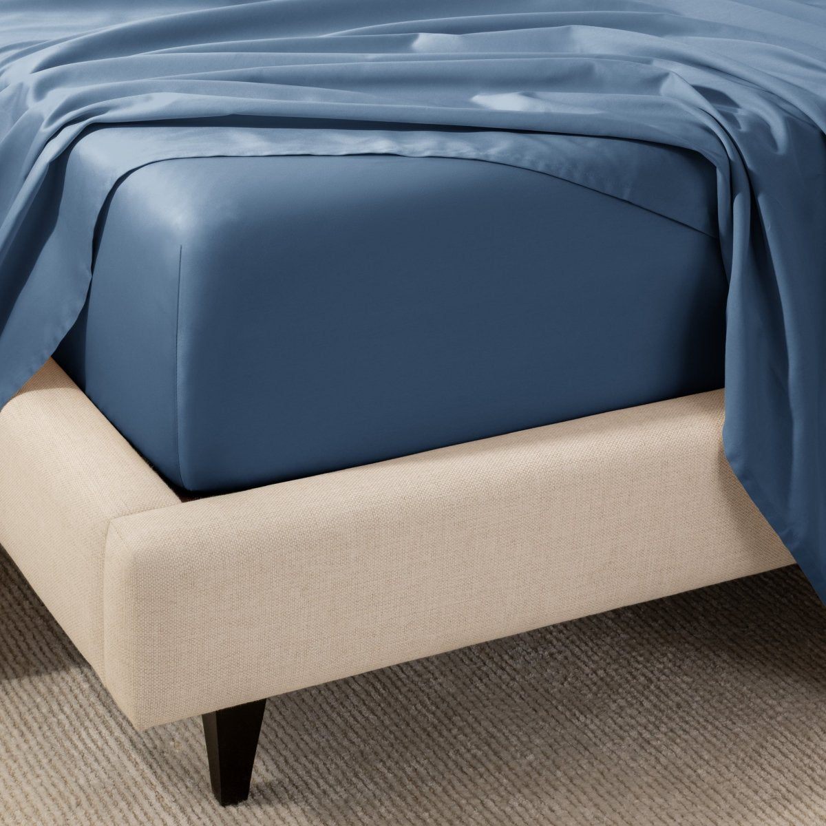 A close-up of the corner of a bed with a fitted sheet and matching flat sheet.