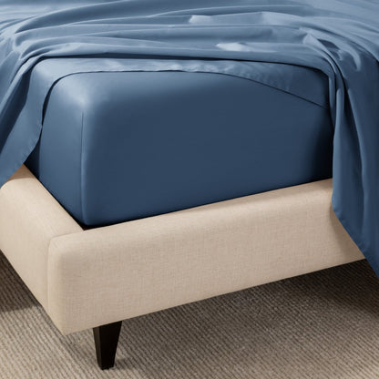 A close-up of the corner of a bed with a fitted sheet and matching flat sheet.
