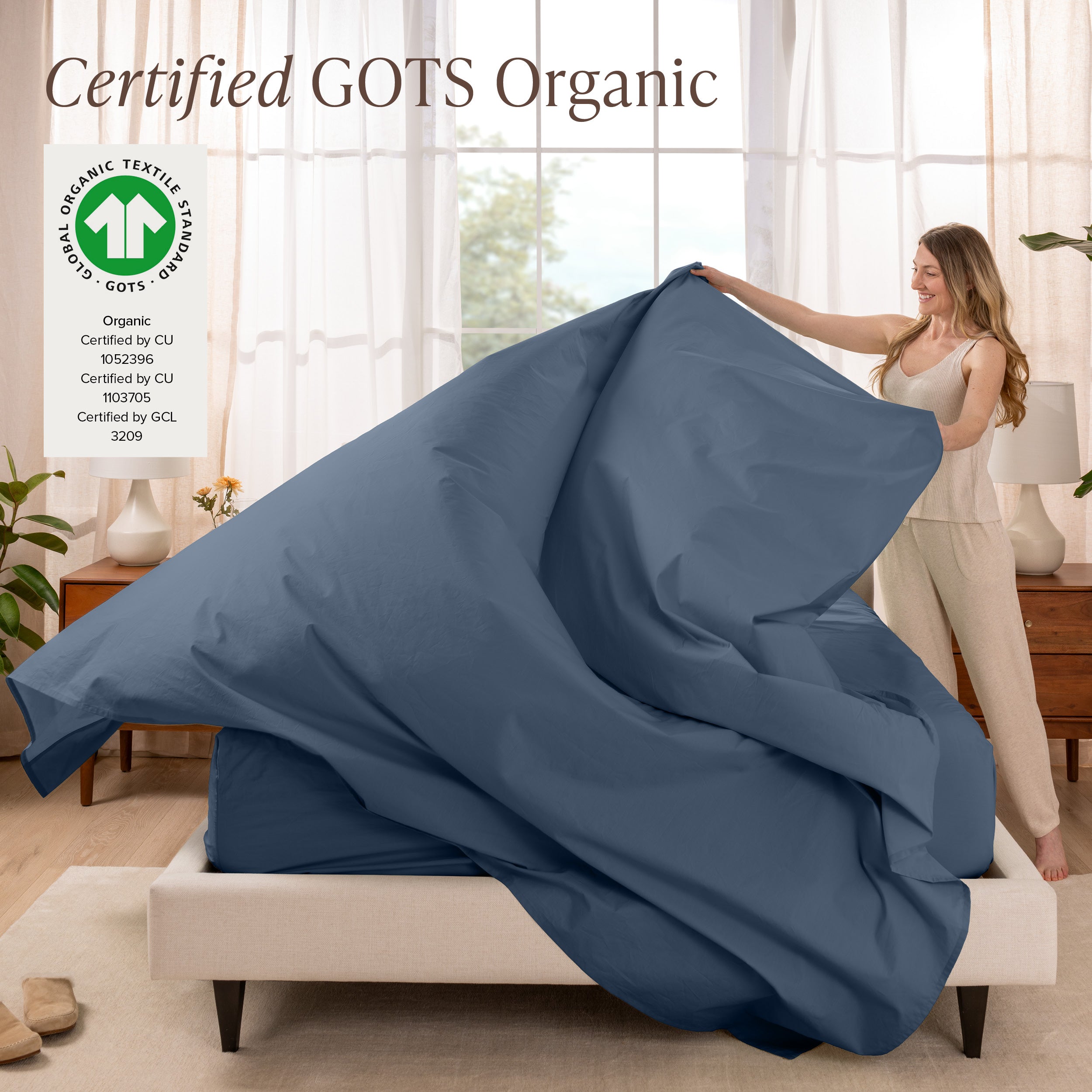 A woman is making a bed with organic cotton percale sheets