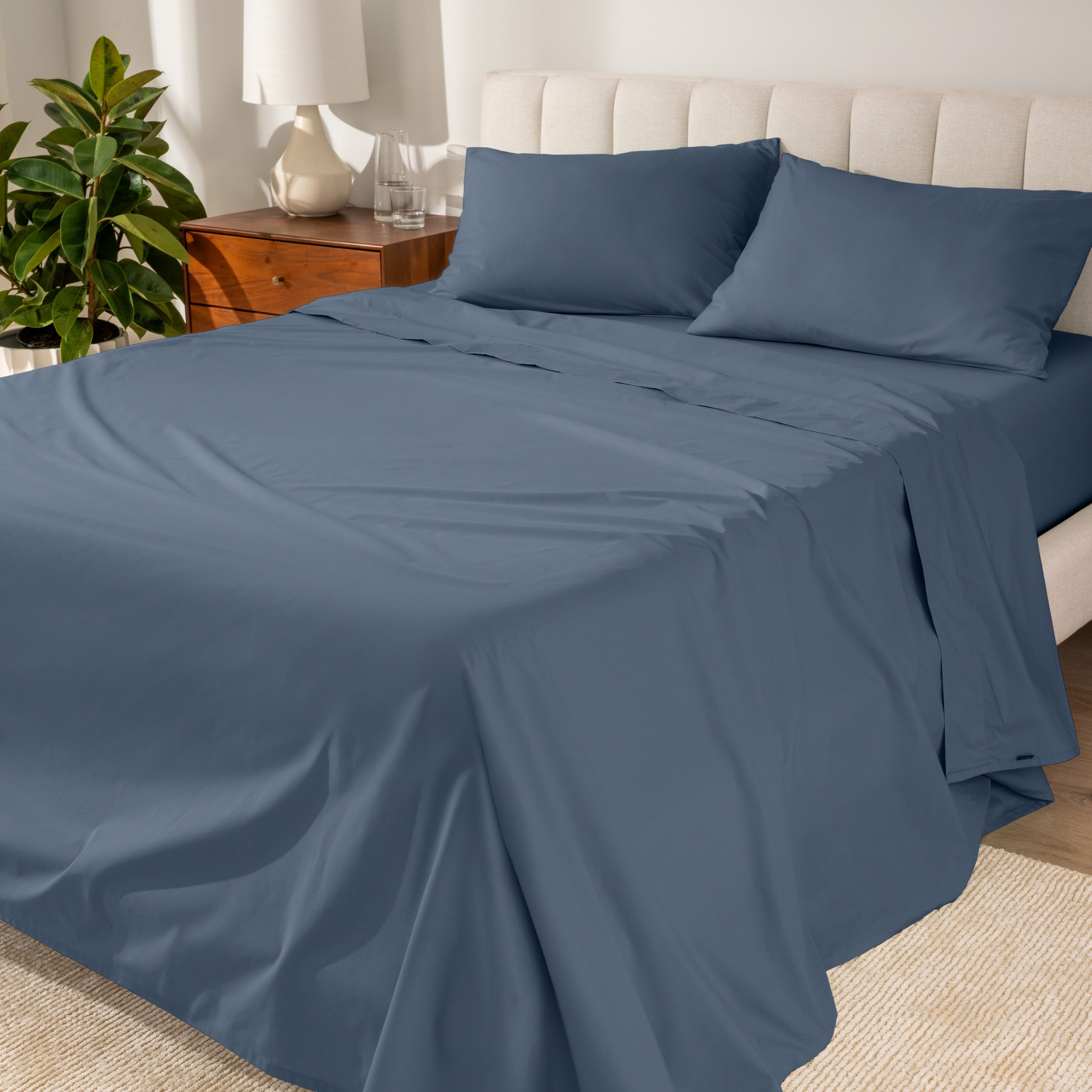 Percale sheets on a bed with a cream colored frame and headboard