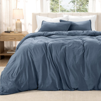 Washed duvet set on a bed in a bright bedroom with a lamp and window.