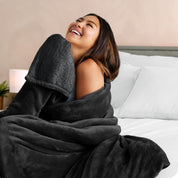 A woman smiling while wrapped in a sherpa blanket