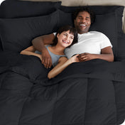 A couple is lying in bed with a comforter and sheets over them