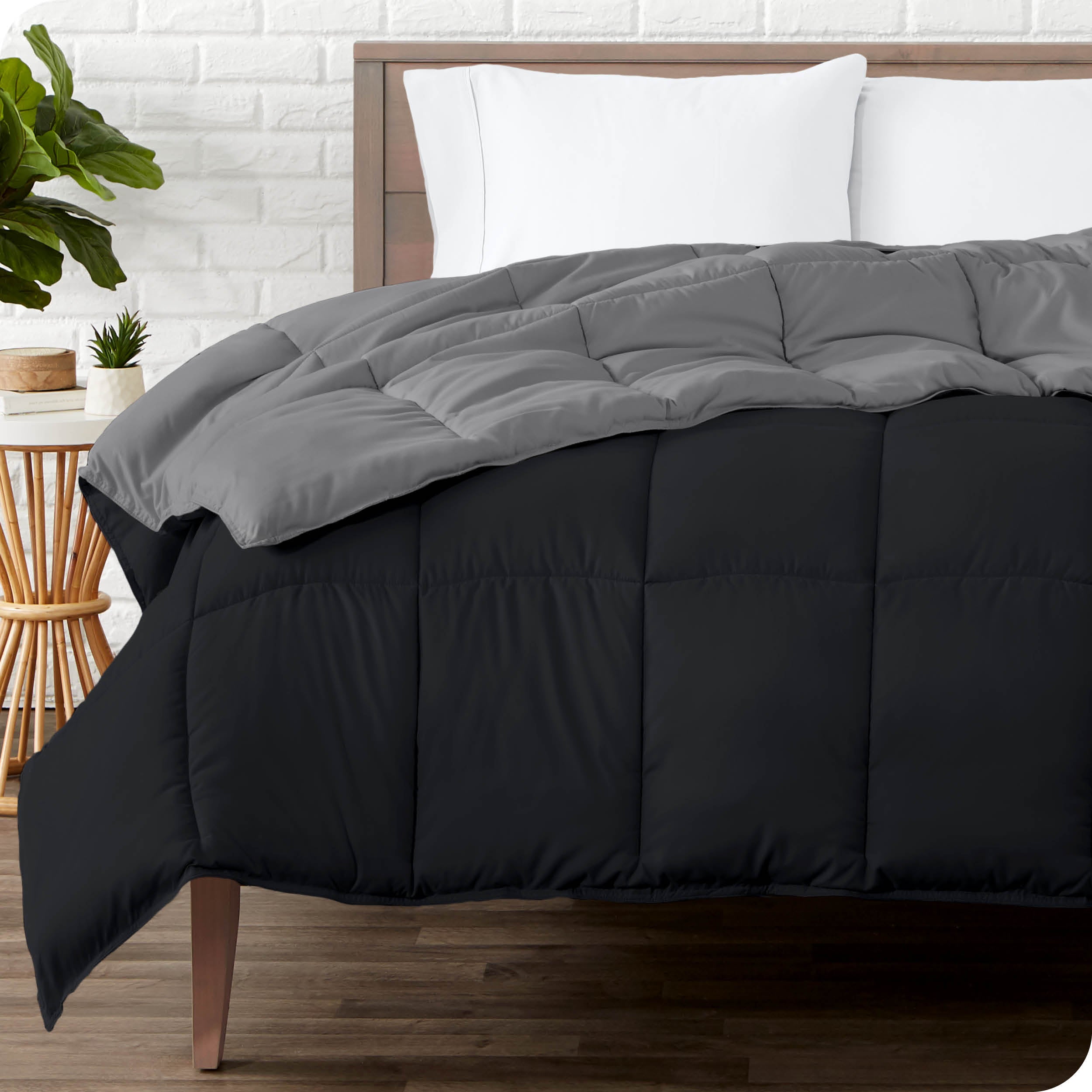 Wooden bed frame with a reversible comforter on the mattress. The comforter is folded back showing the two different colored sides.
