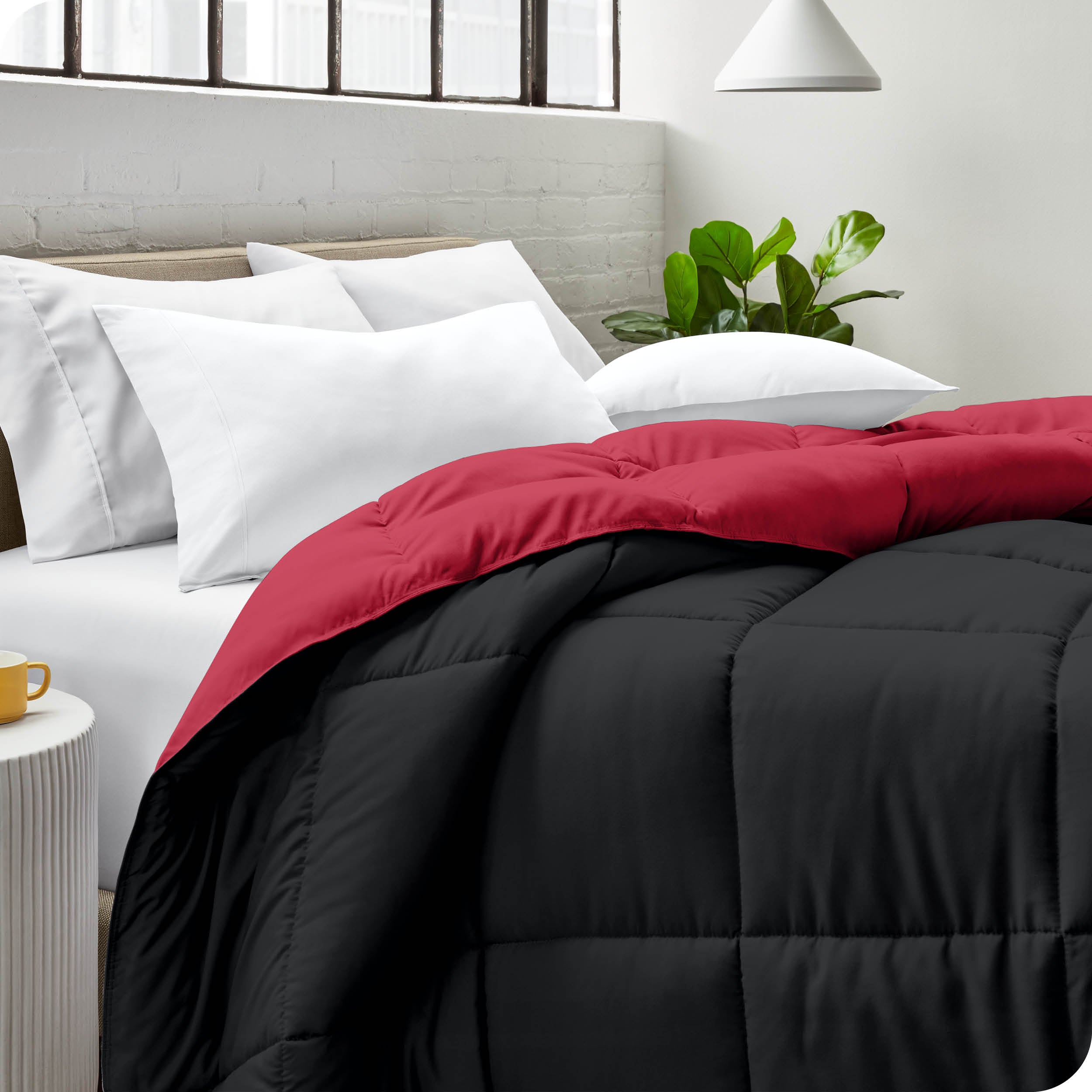 Close up of a comforter on a bed folded over itself. There are also 4 pillows on the bed.