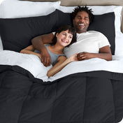 A couple is lying in bed with a comforter and sheets over them