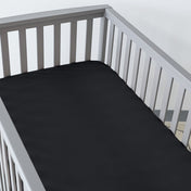 Gray crib with a fitted sheet on the mattress