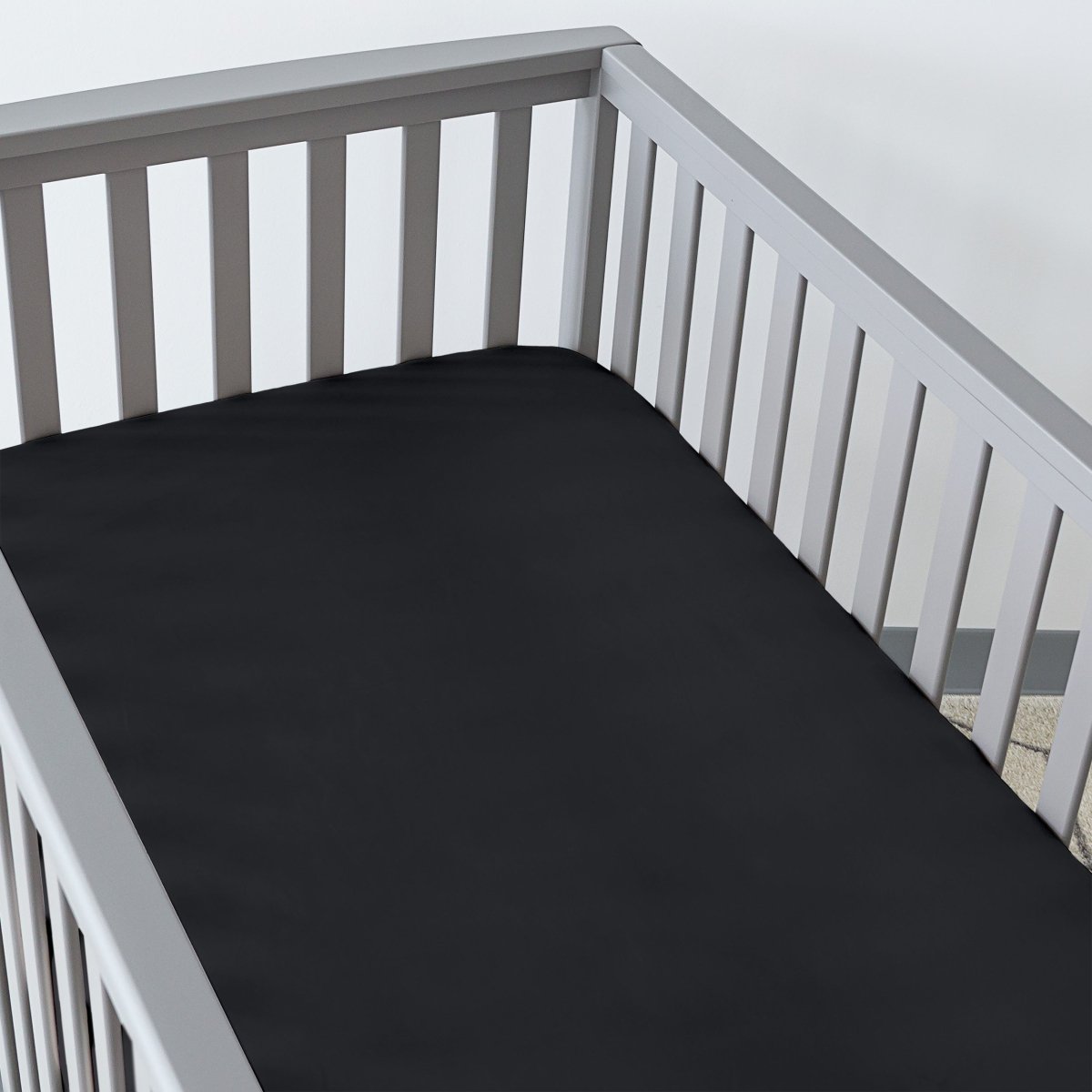 Gray crib with a fitted sheet on the mattress