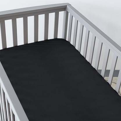 Gray crib with a fitted sheet on the mattress