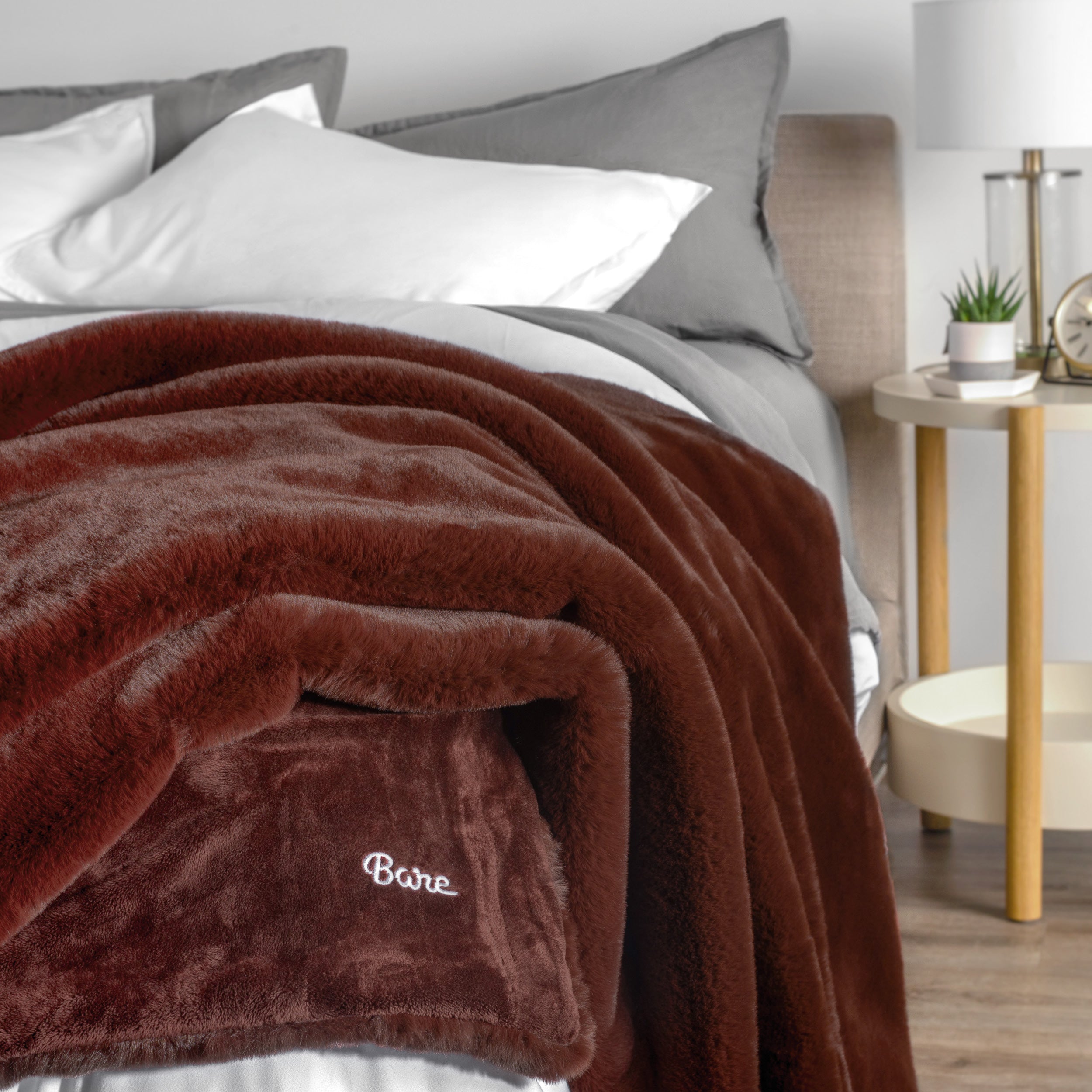 Blanket with 'Bare' branding on a bed in a bedroom setting