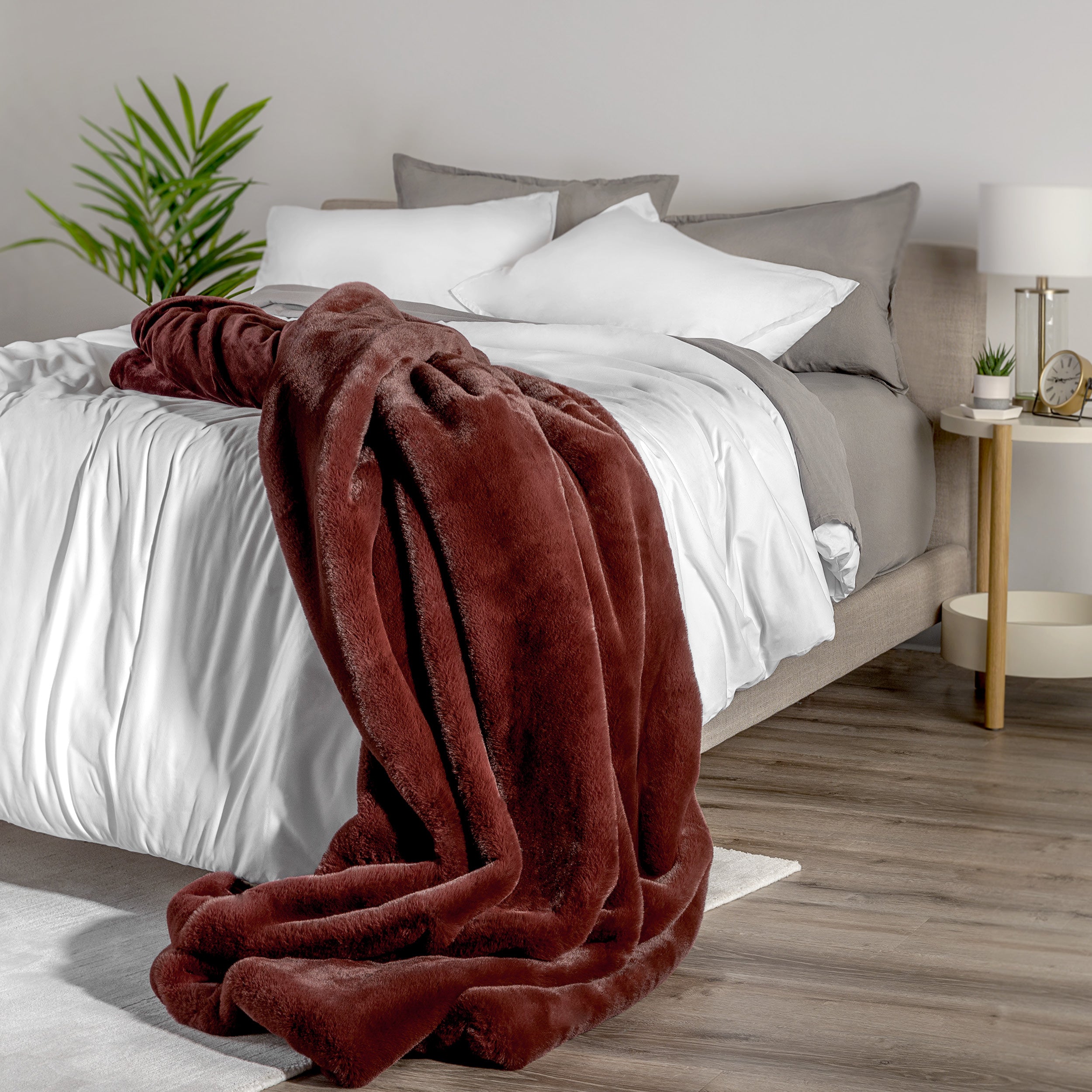 Blanket draped over a bed in a bedroom setting with a nightstand and lamp.