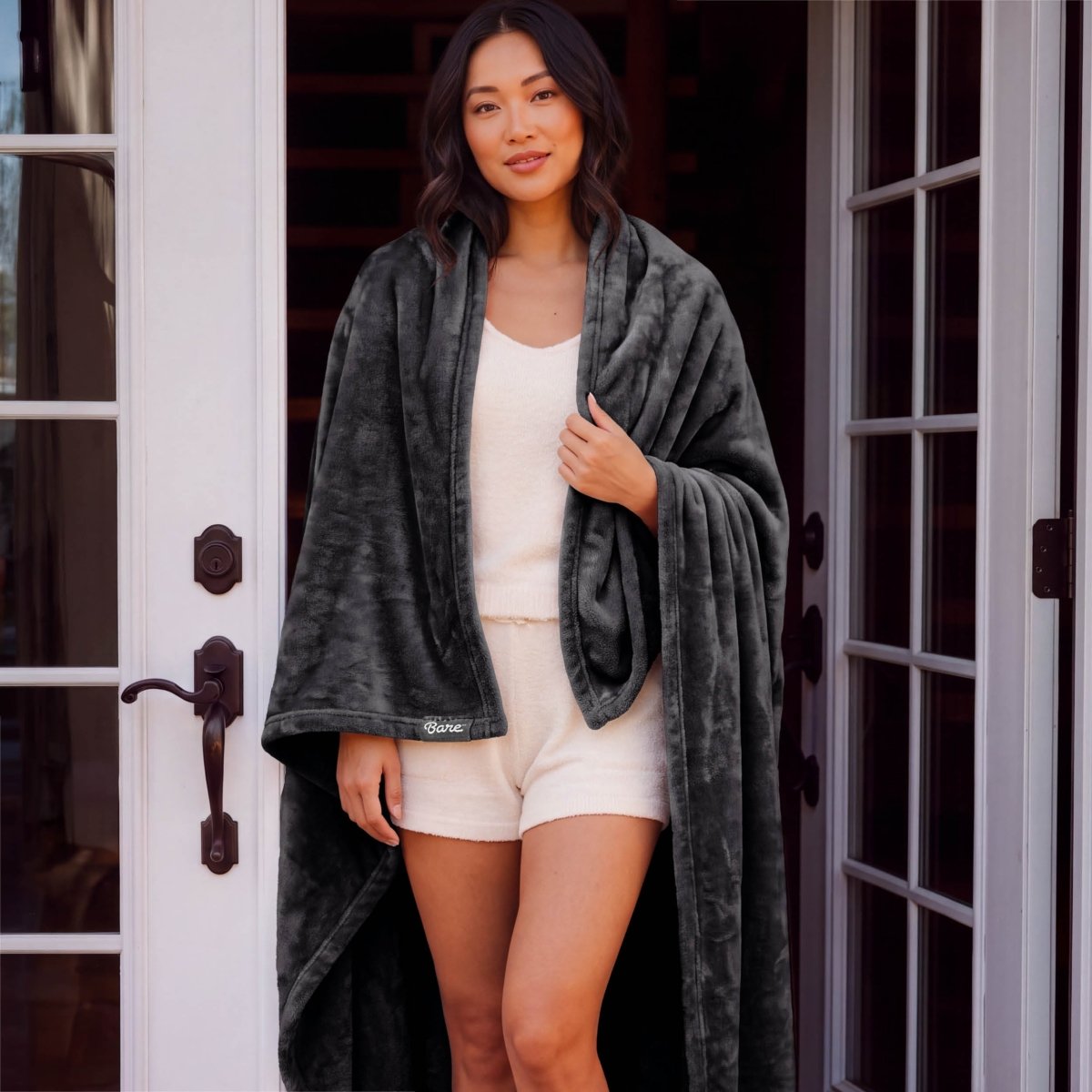 A woman standing with a microplush blanket wrapped around her