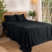 Bamboo sheets on a bed in a bedroom with plants and a lamp.