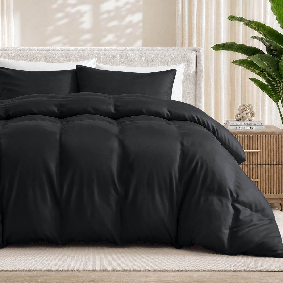 Black duvet cover set on a bed in a bedroom setting with a plant and nightstand.