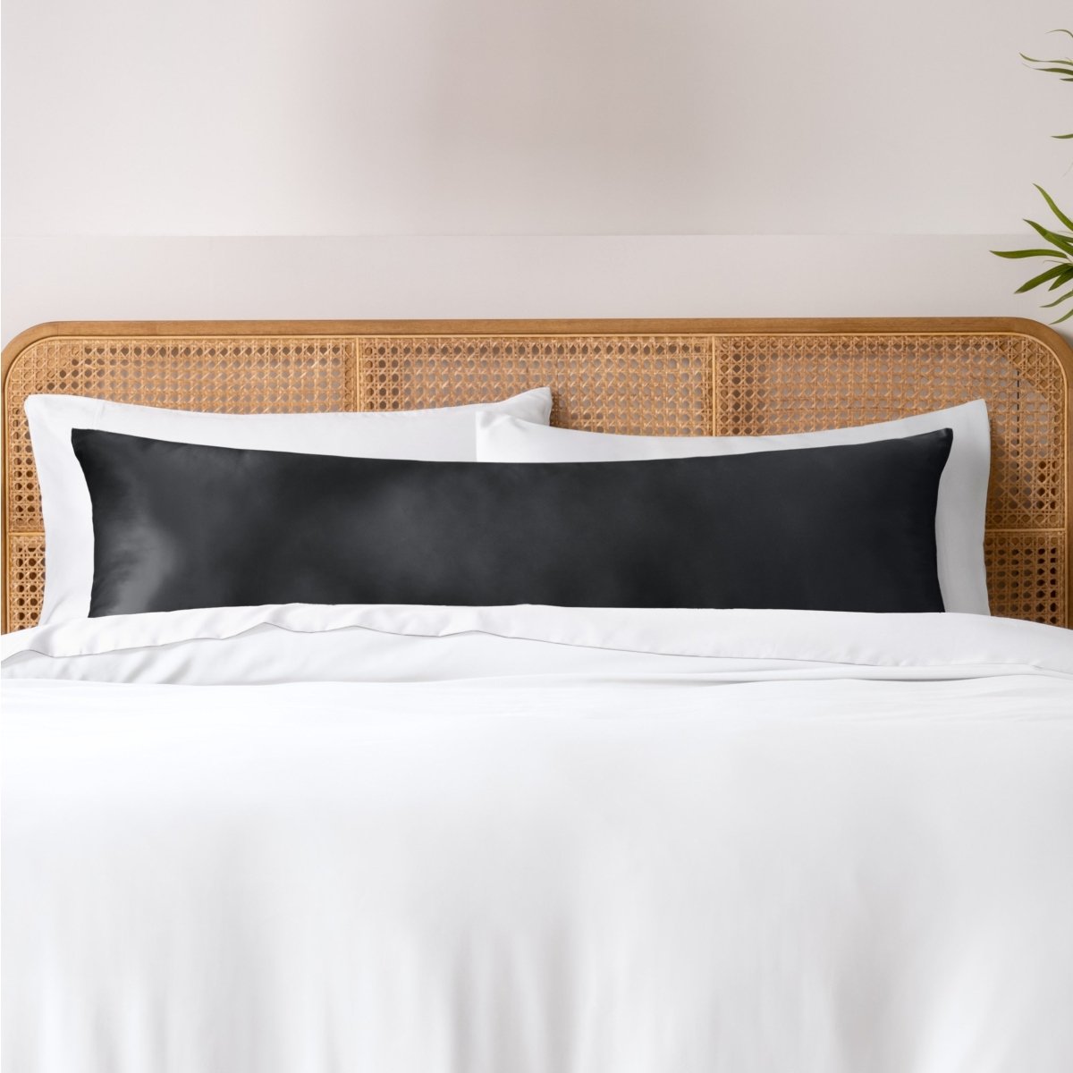 Pillows, sheets and a duvet cover on a bed with a wicker headboard and light gray bedding.