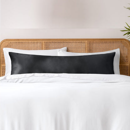 Pillows, sheets and a duvet cover on a bed with a wicker headboard and light gray bedding.
