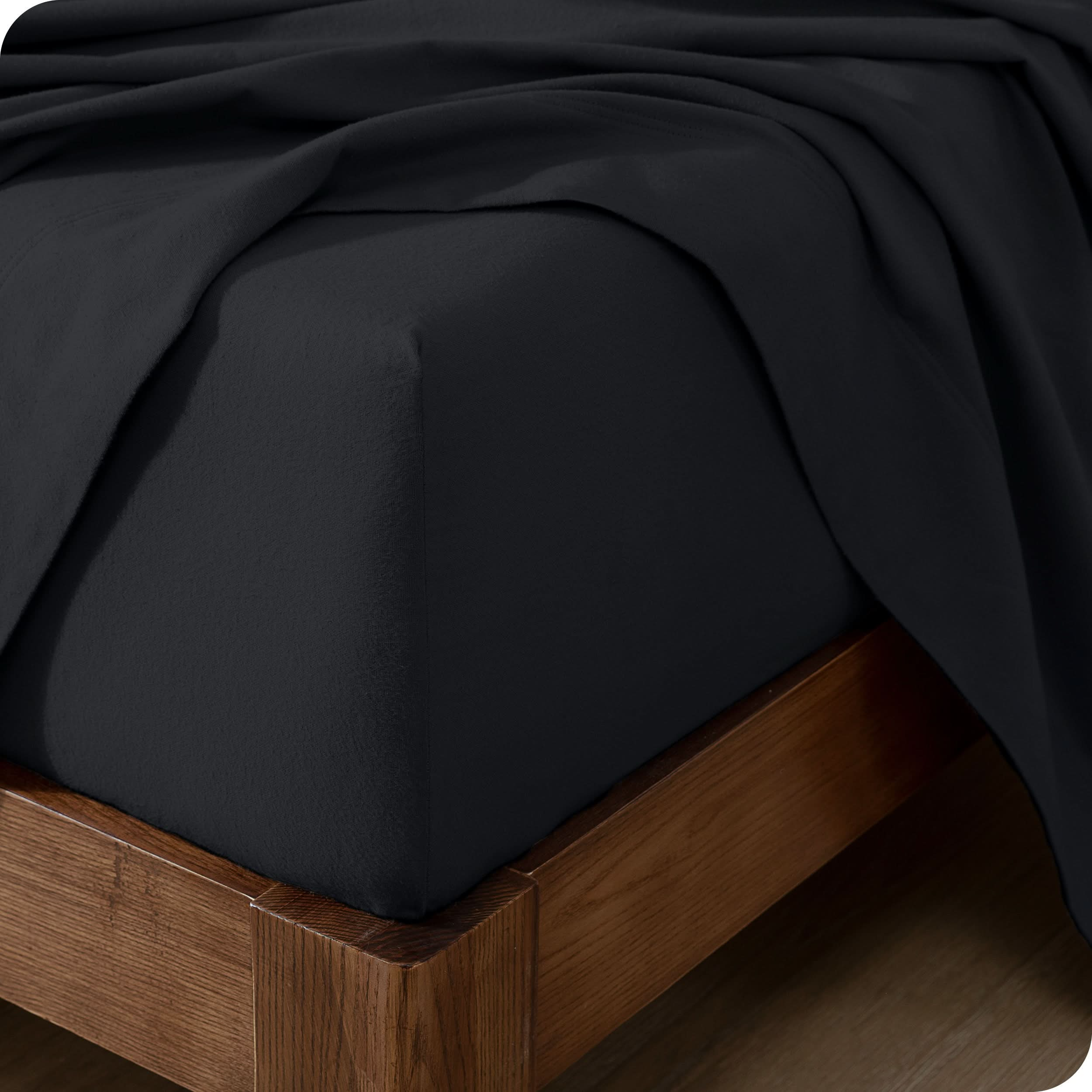 Close up of the corner of a mattress with a flannel fitted sheet and flat sheet on it