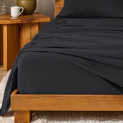 Bed with flannel bedding and wooden headboard and nightstand next to it.