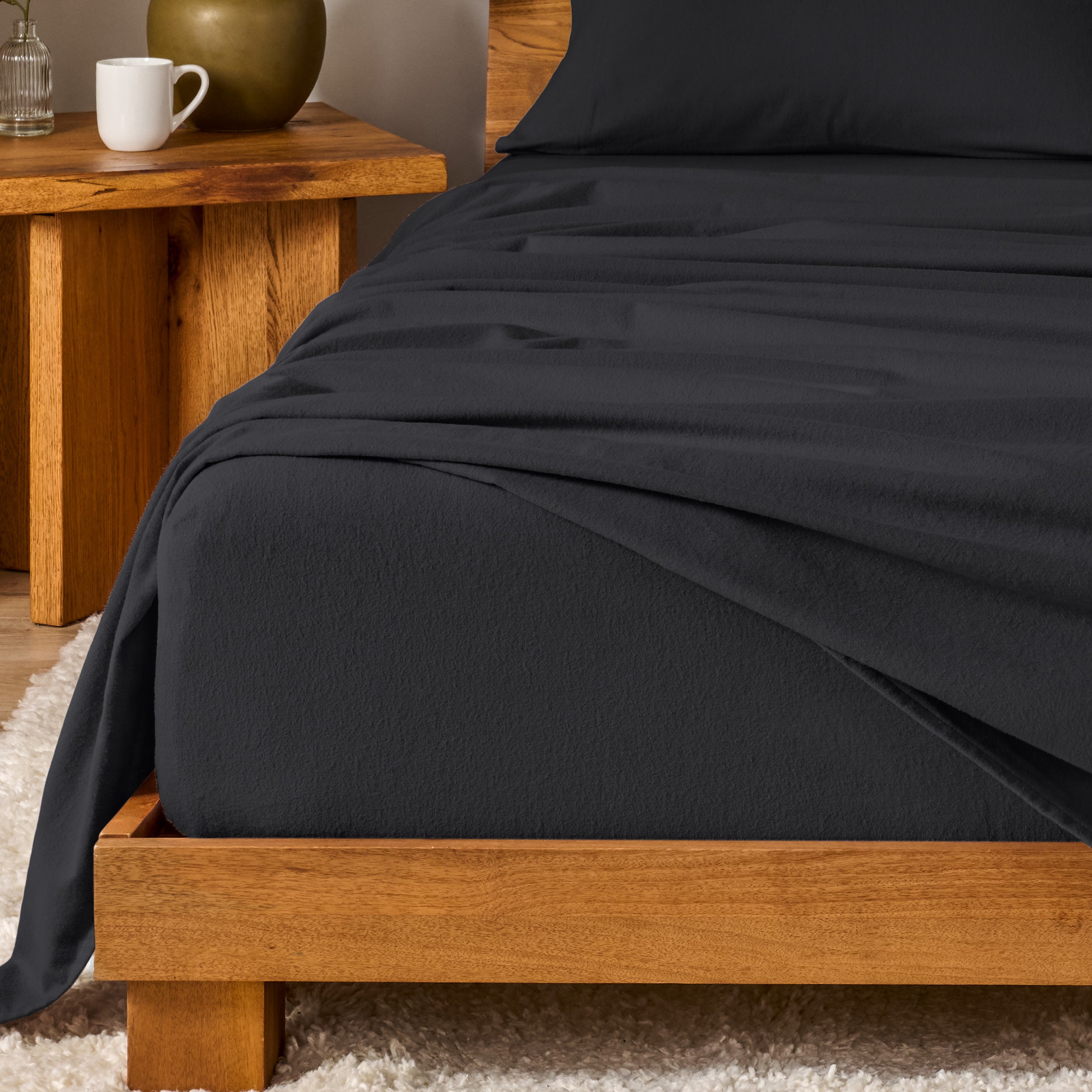 Bed with flannel bedding and wooden headboard and nightstand next to it.