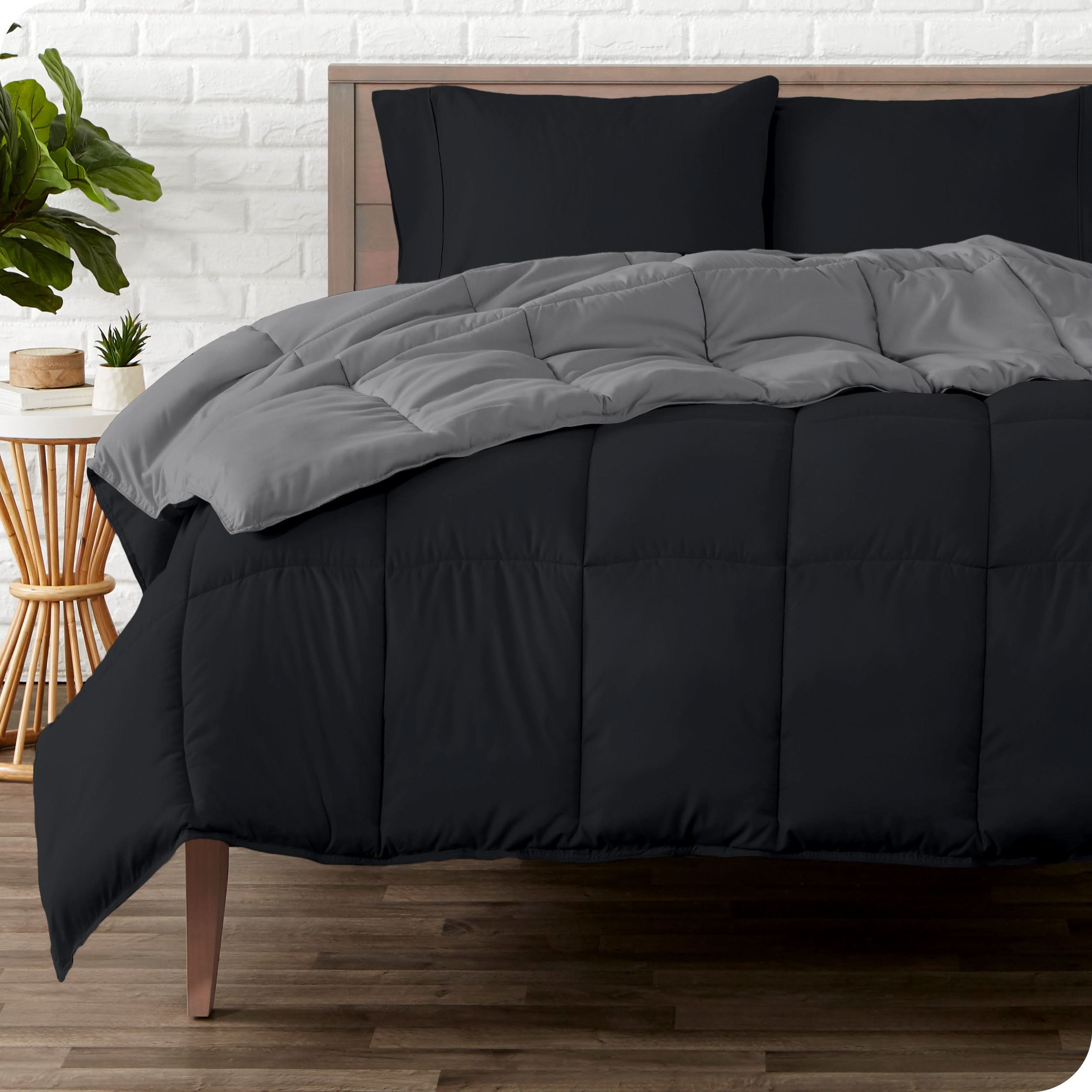 A wooden bed frame with a reversible comforter and sheet set on the mattress