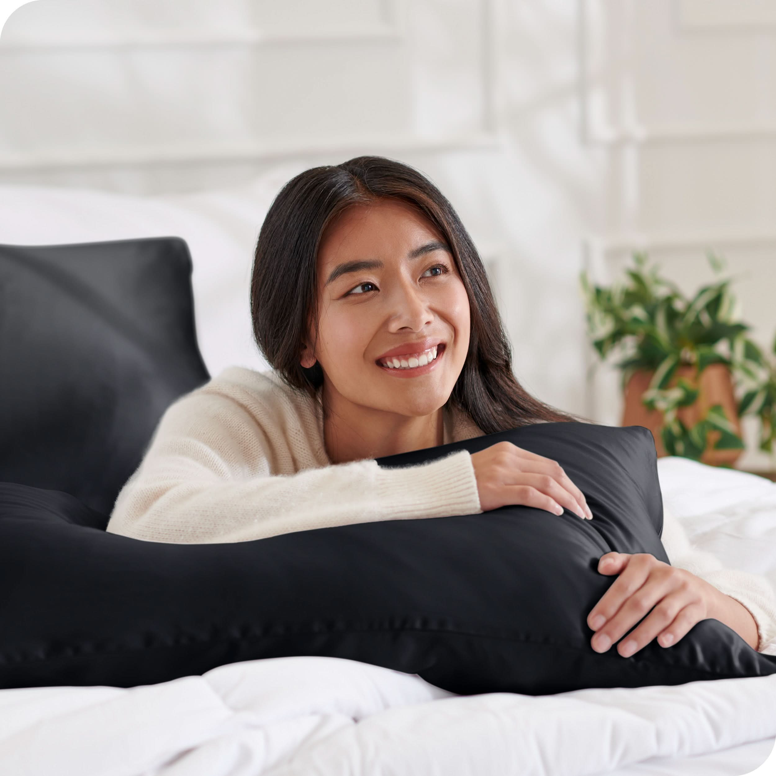 A woman on a bed with a silk pillowcase covered pillow