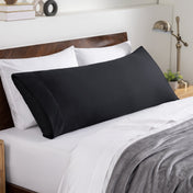 Bed sheets and pillows on a neatly made bed with a wooden headboard.