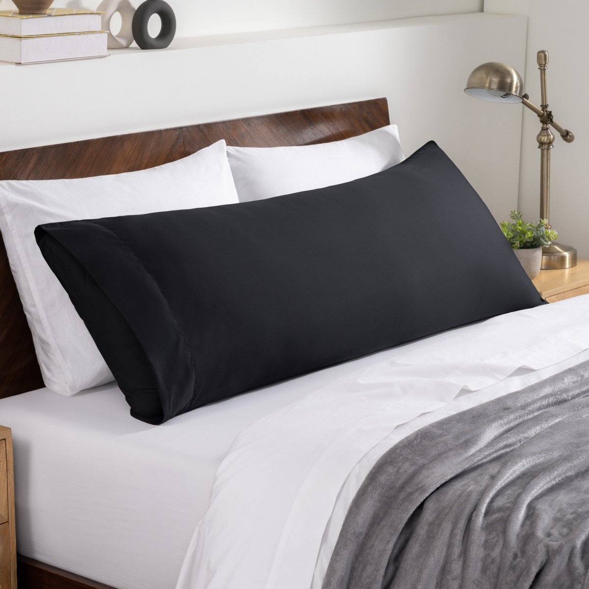 Bed sheets and pillows on a neatly made bed with a wooden headboard.