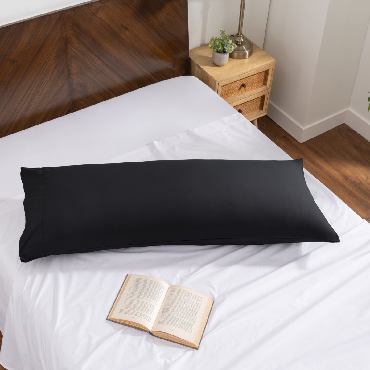 Pillowcase on a body pillow with a wooden headboard and plant in the background