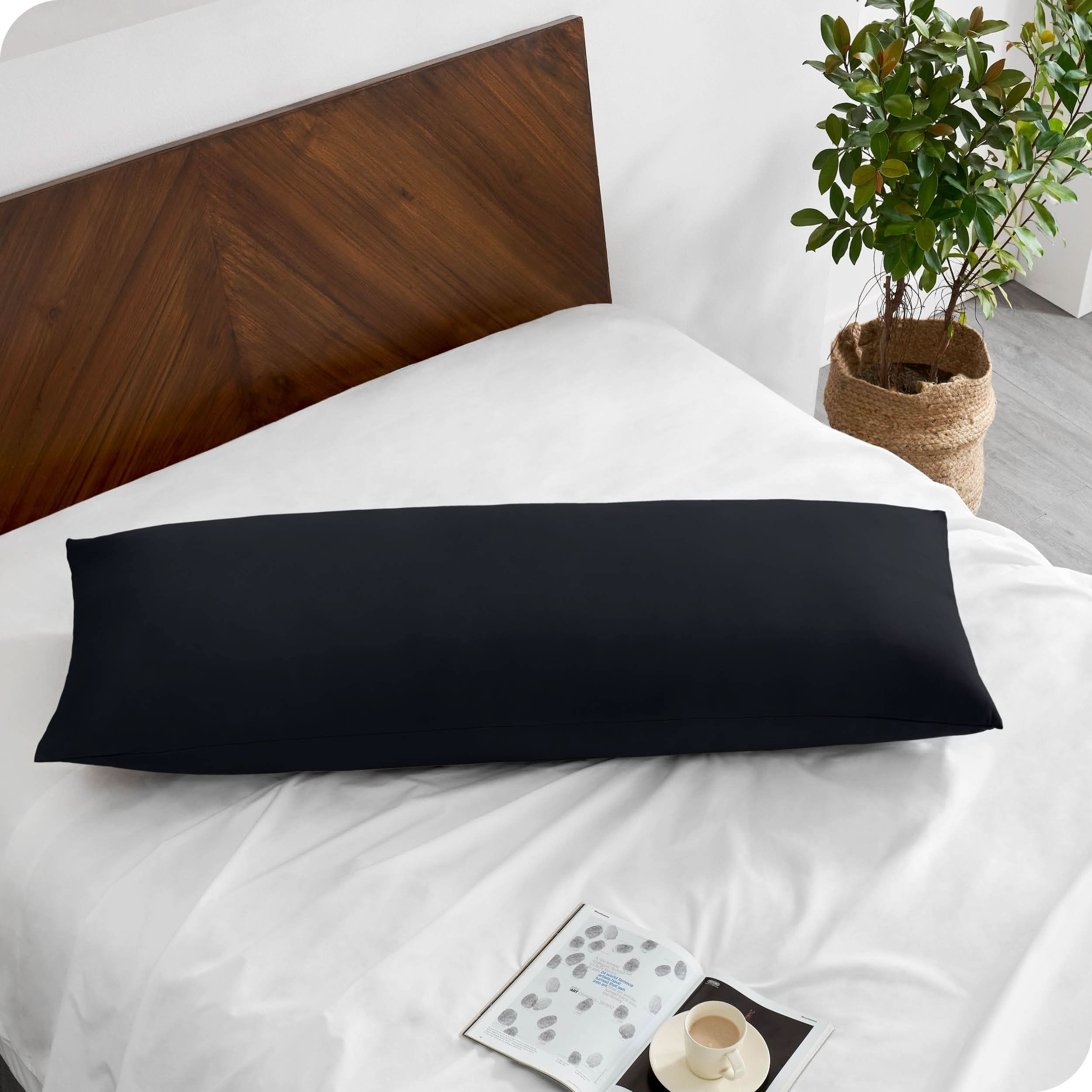 A body pillow cover on a pillow on a bed made with all white bedding